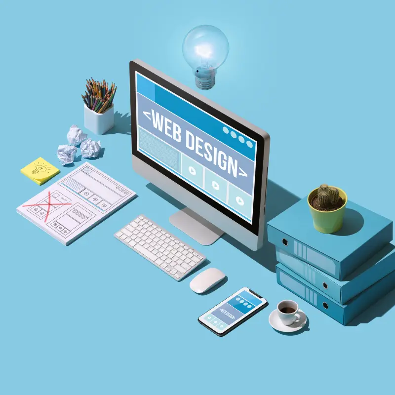 Scrivania organizzata con computer che mostra “Web Design”, smartphone, tazza di caffè e materiali da ufficio su sfondo azzurro.